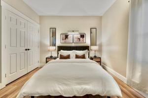 a white bedroom with a large bed with two lamps at BRAND NEW Cozy Modern Bungalow w/Hot Tub+MovieRoom 7 MIN FROM UPTOWN in Charlotte