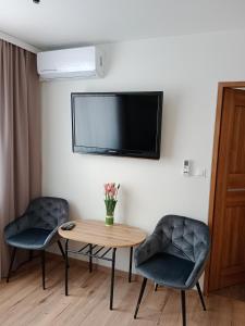 a living room with two chairs and a table and a tv at Pensjonat Mickiewicz in Sandomierz