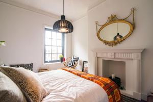 1 dormitorio con cama y espejo en la pared en BOHOUSE Moody boho townhouse Macclesfield centre, en Macclesfield