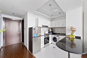 a kitchen with a table and a stainless steel refrigerator at Silkhaus Modern Luxurious Studio Near Dubai Silicon Oasis Shopping Mall in Dubai