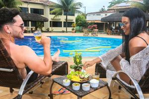 un hombre y una mujer sentados en una mesa con un plato de comida en Hotel Real Comandatuba en Ilha de Comandatuba