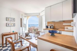 バンドールにあるStudio Damier - 3 étoiles - Welkeysの白いキャビネットとテーブルと椅子のあるキッチン