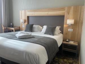 a large bed in a hotel room with two tables at Hotel Le Cercle in Cherbourg en Cotentin