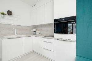 a kitchen with white cabinets and a microwave at Rogowo Pearl Turquoise Apartments Near The Sea with FREE PARKING by Renters in Rogowo