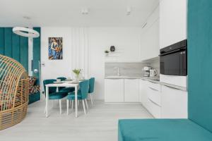 a kitchen with a table and blue chairs at Rogowo Pearl Turquoise Apartments Near The Sea with FREE PARKING by Renters in Rogowo