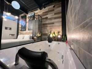 a bathroom with a tub with a chair and a bed at Hotel Lleras Medellin in Medellín