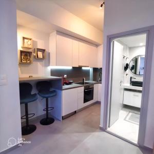 una cocina con armarios blancos y 2 taburetes en Monastiraki Heart - Luxury Apartment Athens en Atenas