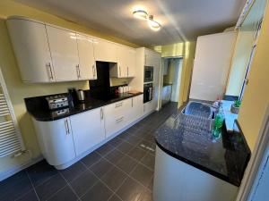 a kitchen with white cabinets and a black counter top at Home Away From Home - Perfect For Contractors in Newark upon Trent +21 photos