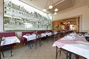 a restaurant with tables and chairs and a large painting on the wall at Contact Hôtel de la Gare et son restaurant Côte à Côte in Autun