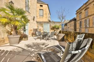 a patio with chairs and a table and trees at La Villa des Consuls - Gîte de tourisme de charme in Sarlat-la-Canéda