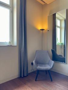 une chaise dans une chambre avec un miroir et une fenêtre dans l'établissement Home nearby timeout, à Lisbonne