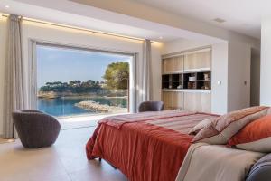 een slaapkamer met een groot raam met uitzicht op een meer bij VILLA LA ROMANELLA in Carry-le-Rouet +22 foto's