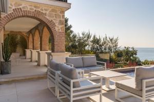 een terras met stoelen en tafels en de oceaan bij VILLA LA ROMANELLA in Carry-le-Rouet