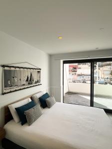 a bedroom with a large white bed with a large window at Les Cabanons de Fonfon in Marseille