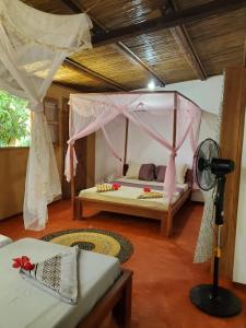 a bedroom with a bed with a canopy and a fan at Les Citronniers in Sainte Marie