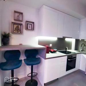 una cocina con armarios blancos y taburetes azules en Monastiraki Heart - Luxury Apartment Athens en Atenas