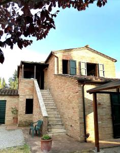 une maison en briques avec des escaliers et une chaise verte dans l'établissement Agriturismo Carpineto, à Asciano