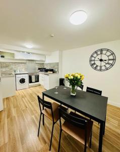 uma cozinha com uma mesa e um relógio na parede em The Suffolks, 1 Bedroom Flat em Cheltenham