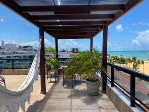 若昂佩索阿的住宿－Bela Hospedagem - Marinas Flat - Excelente localização na orla de Cabo Branco，设有带吊床的阳台,享有海滩美景