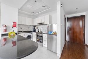 a kitchen with white cabinets and a black counter top at Silkhaus Chic Studio Near Silicon Oasis Shopping Mall in Dubai