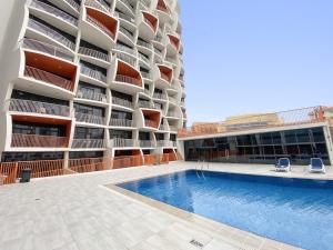 un bâtiment avec une piscine en face d'un bâtiment dans l'établissement Silkhaus Chic Studio Near Silicon Oasis Shopping Mall, à Dubaï