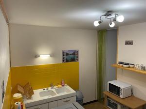 a bathroom with a sink and a yellow wall at Au pays d'Hector Berlioz in La Côte-Saint-André