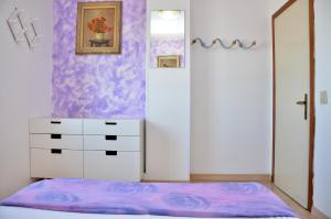 um quarto com uma cómoda branca e uma parede roxa em Condominio Adriatico em Bibione