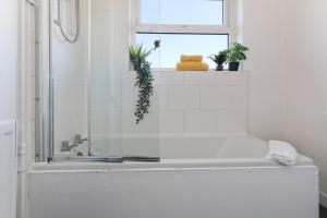 a white bathroom with a tub and a window at Prime Location Stylish 4-bed House Near Trent Br in Nottingham