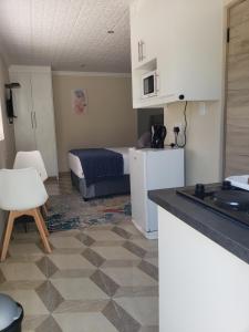 a room with a bed and a kitchen with a table at HARESCA LUXURY Accommodation Bellville in Cape Town