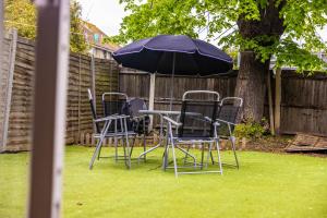 a group of chairs and an umbrella in a yard at Pristine Relocation 3-Bed House in London in London