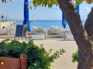 a beach with tables and chairs and the ocean at IRIA BEACH Sea and Sun in Paralía Iríon