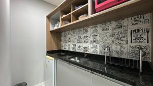 uma cozinha com um lavatório e muitos desenhos na parede em 09- Studio lindamente decorado! Ideal para casal!!! em Curitiba