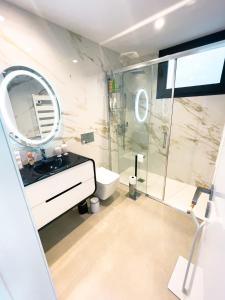 uma casa de banho com um chuveiro, um lavatório e um espelho. em Casa Tranquilidade - Casa moderna com piscina em Guimarães