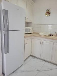 a kitchen with white cabinets and a white refrigerator at 24 Maple Gardens in Bridgetown