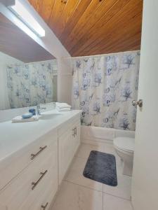 a white bathroom with a sink and a toilet at 24 Maple Gardens in Bridgetown