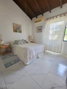 a white bedroom with a bed and a window at 24 Maple Gardens in Bridgetown