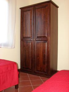 un armario de madera en una habitación con cama roja en Borgo Nicoletta Case per le vacanze, en Filandari