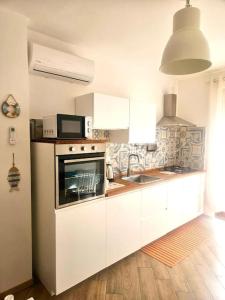 a kitchen with white cabinets and a microwave at CLhome: 3 minuti dal mare in Alghero