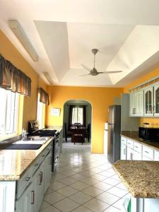 a large kitchen with yellow walls and a ceiling at Kay Marni: Your Saint Lucian home in Gros Islet