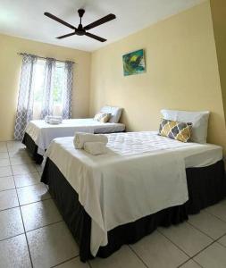 a bedroom with two beds with white sheets and a fan at Kay Marni: Your Saint Lucian home in Gros Islet