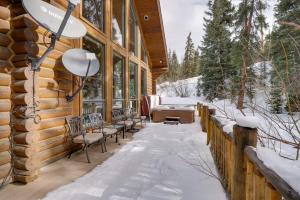 un porche de una cabaña de madera en la nieve en Rustic Breckenridge Cabin with Hot Tub and Deck, en Breckenridge