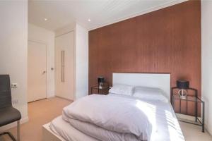 um quarto com uma cama branca e uma parede de madeira em Luxury Penthouse 2 bedrooms flat in Canary Wharf em Londres