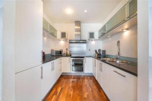 uma cozinha com armários brancos e piso em madeira em Luxury Penthouse 2 bedrooms flat in Canary Wharf em Londres