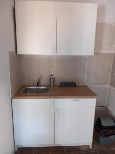 a kitchen with white cabinets and a sink at ΠΕΤΡΟΚΤΙΣΤΟ in Kakopetria