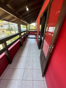 um corredor de um comboio com uma parede vermelha e uma porta em Pousada Via Ferrugem em Garopaba