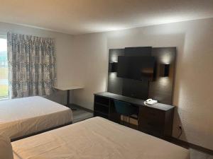 a hotel room with a bed and a desk with a television at Studio 6 Suites Norcross, GA in Norcross