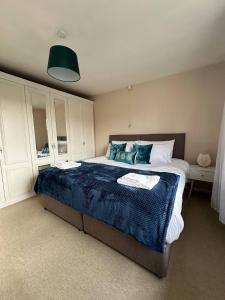 a bedroom with a large bed with a blue blanket at 3 Bed House - Parking - Pool Table - Close to A1 in Balderton