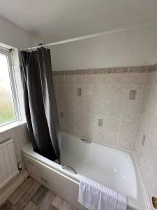 a bathroom with a bath tub with a black shower curtain at 3 Bed House - Parking - Pool Table - Close to A1 in Balderton