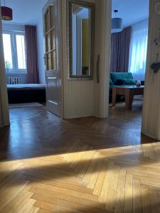 a living room with a mirror and a wooden floor at Apartament centrum in Szczytno