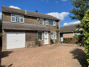 a brick house with white garage doors on a brick driveway at Spacious 5-bed - Perfect For Contractors 